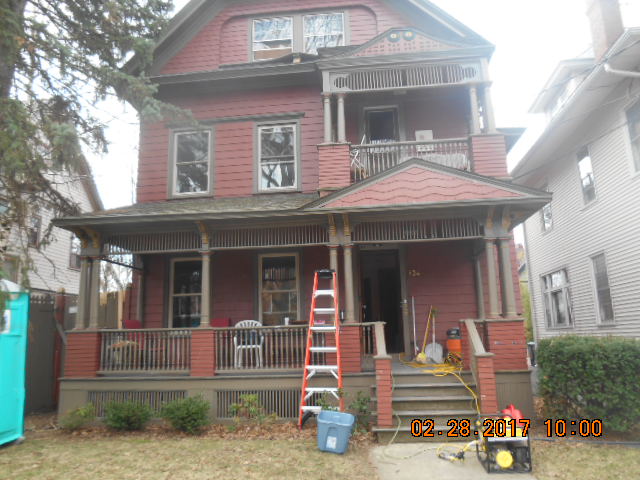 Three story home exterior with worn siding and porch before reconstruction