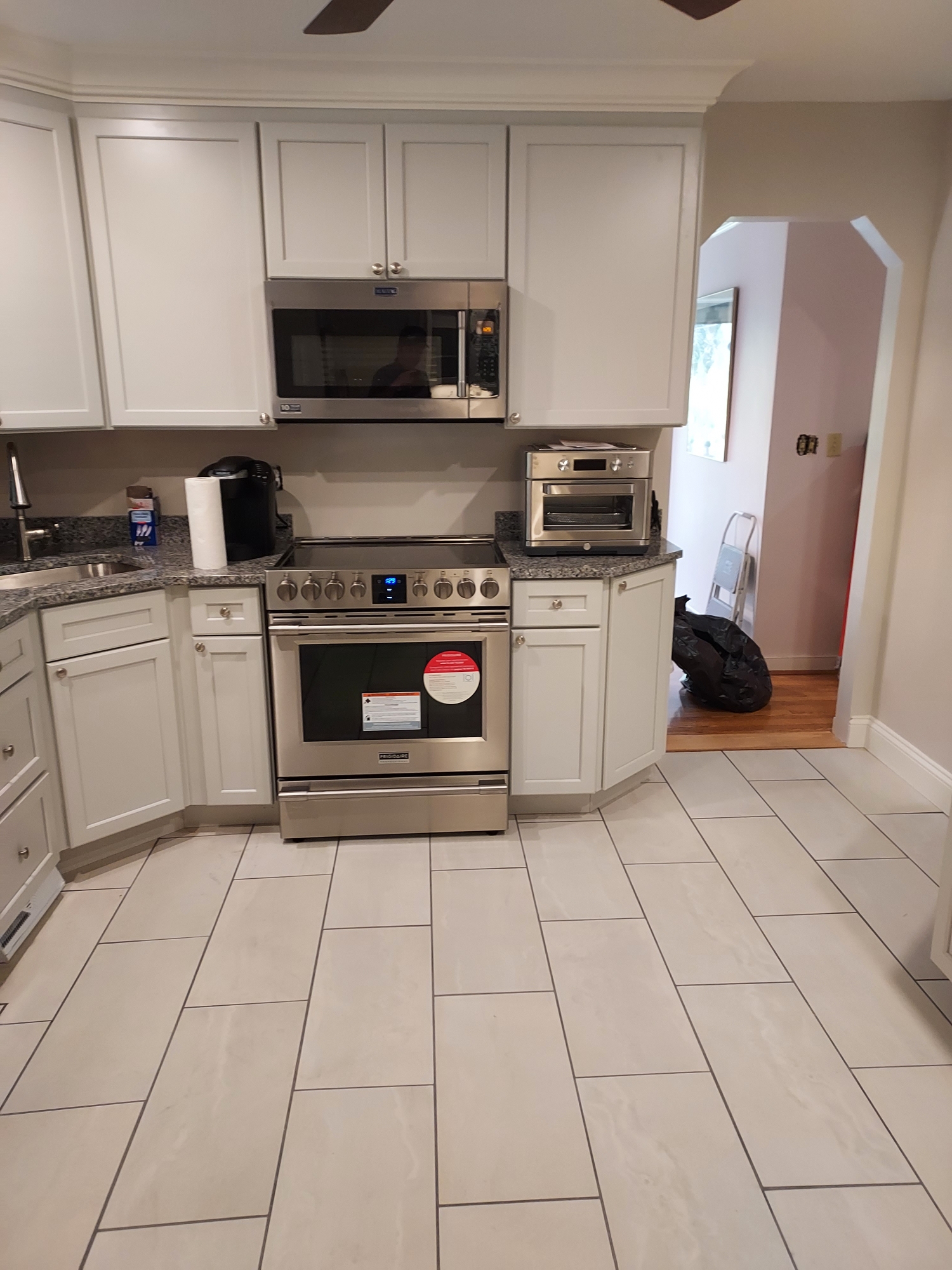 Rebuilt kitchen with white shaker cabinets, granite counters and tile floor