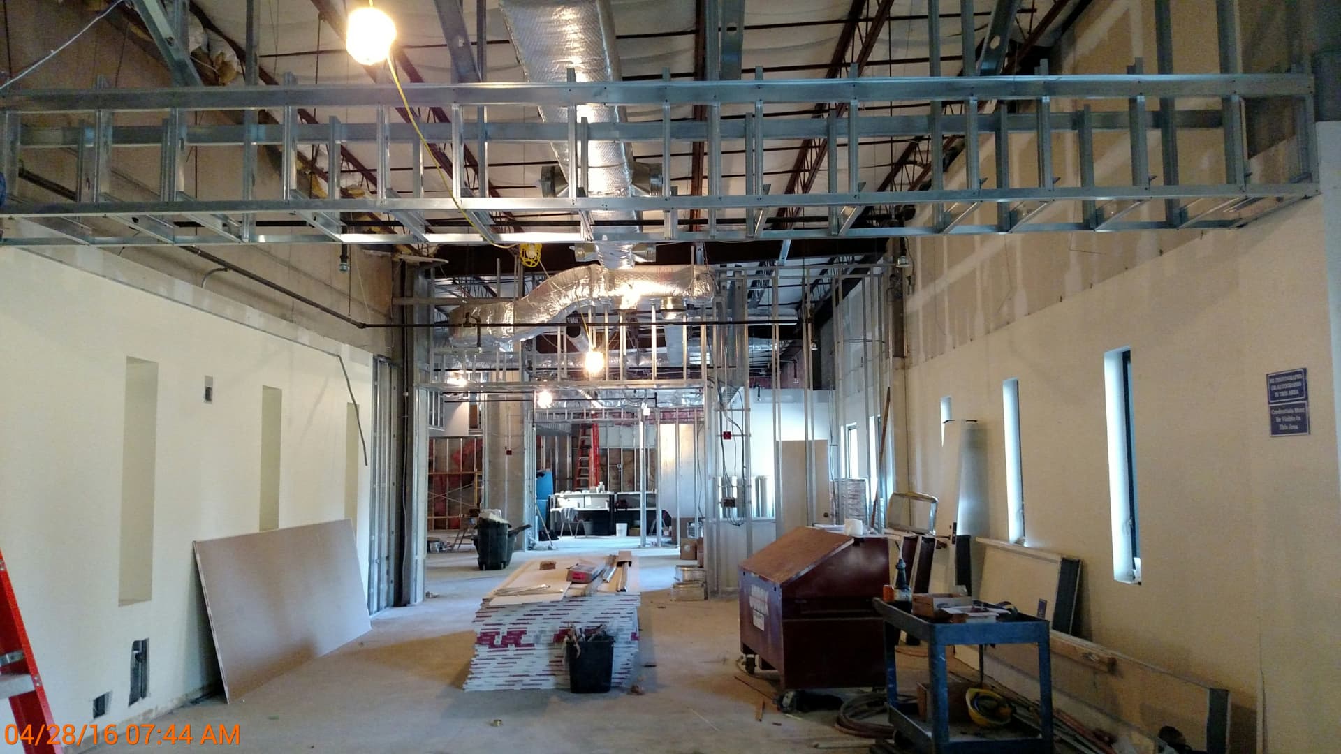 Lounge under construction with metal stud framing and exposed ductwork