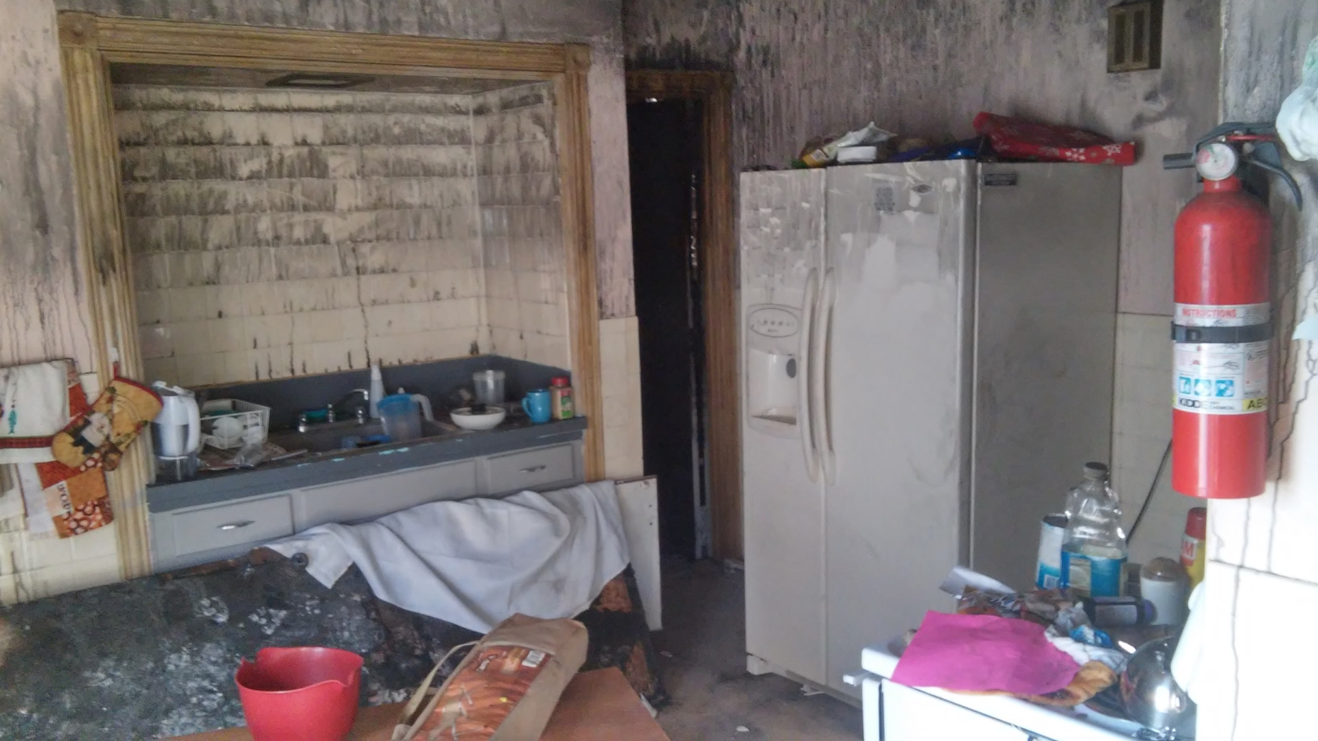 Kitchen covered in soot and debris after a fire
