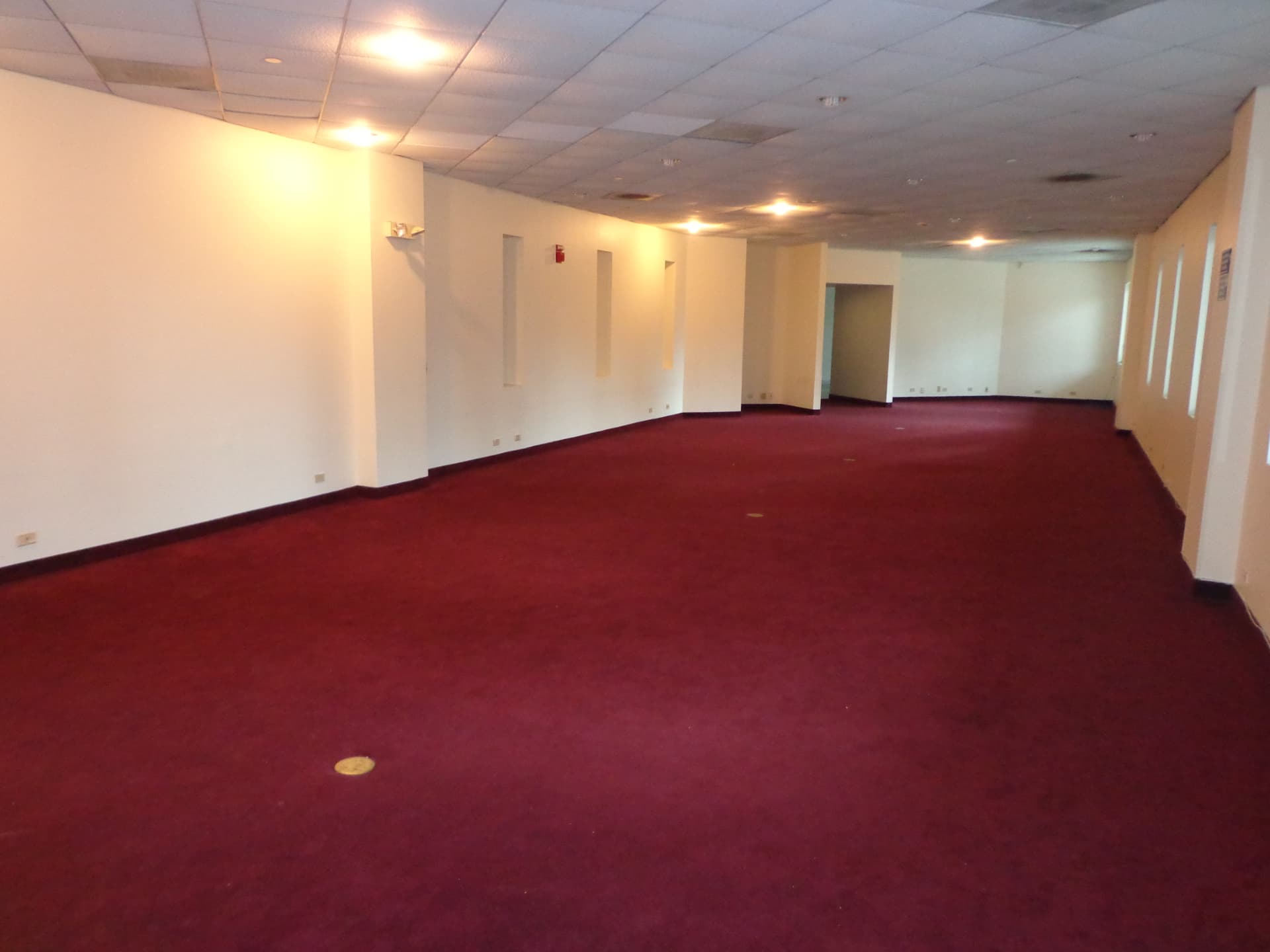 Empty players lounge with dated red carpet and drop ceiling before renovation