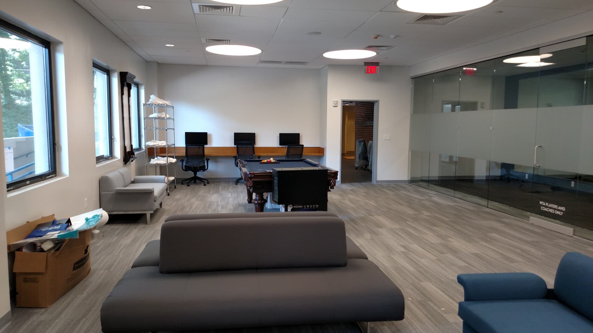 Renovated players lounge with plank flooring, modern seating, workstations and pool table